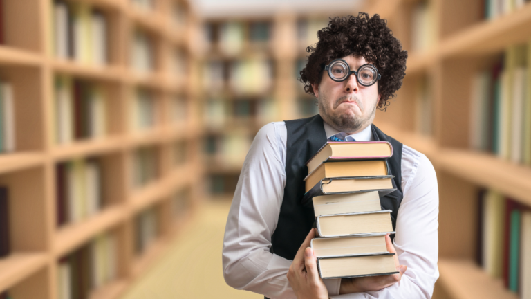 Ragazzo con gli occhiali in biblioteca che trasporta una pila di libri